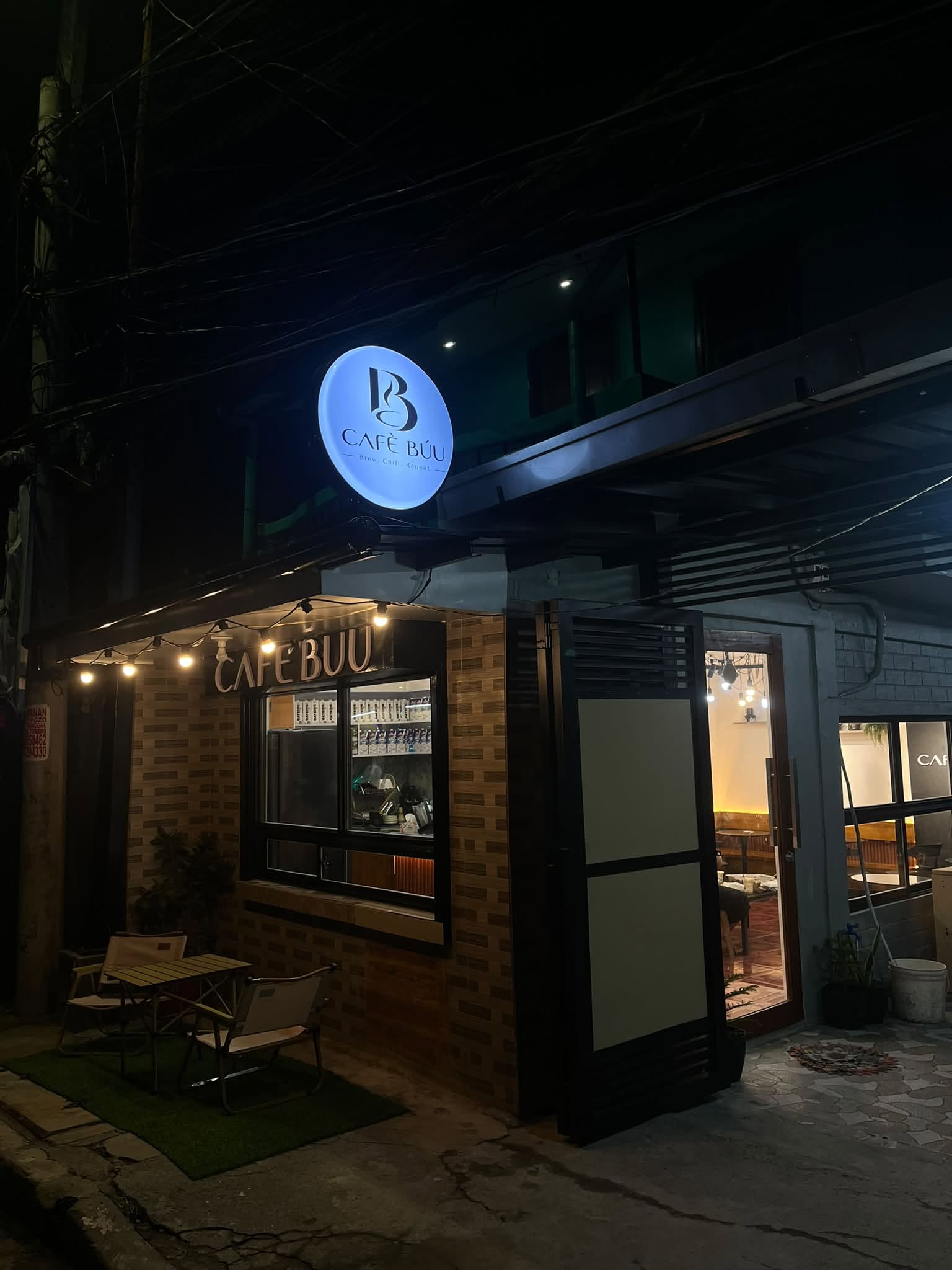 Actual Cafè Búu storefront at night with illuminated circular logo