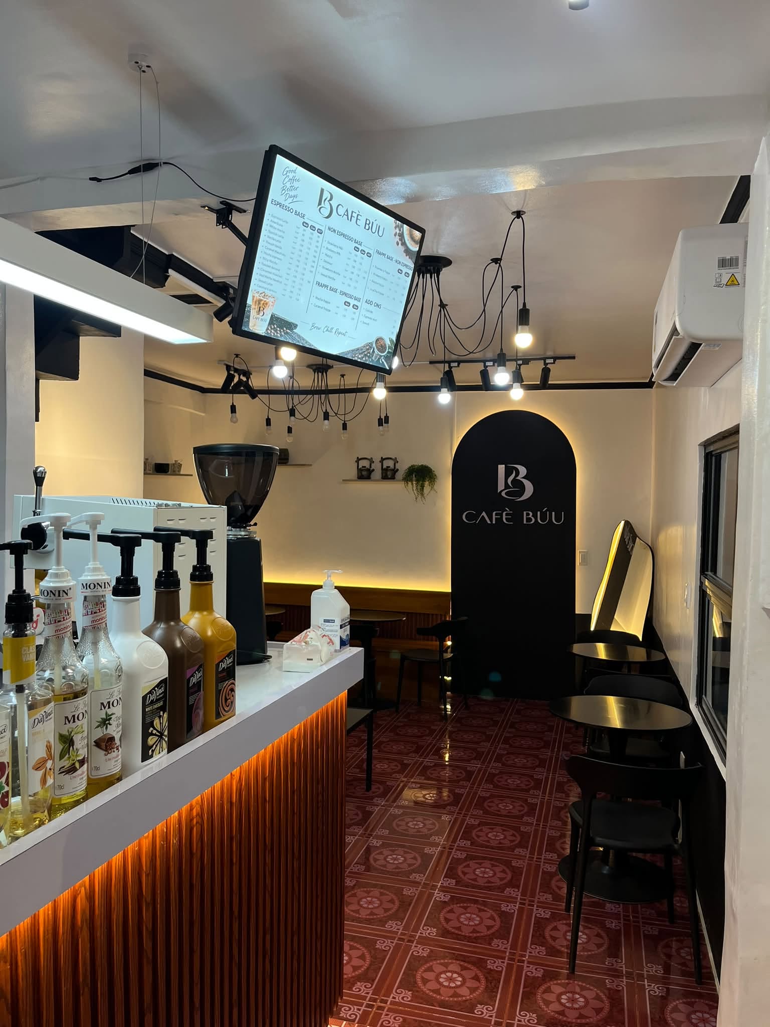 The actual Cafè Búu counter, warm lighting and signature black logo arch